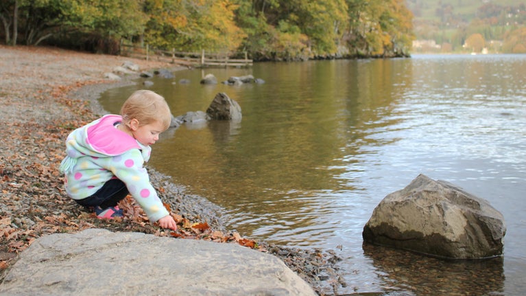 Girl playing with pebbles by the lake at Wray Castle, Cumbria